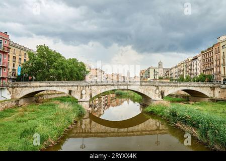 Farbenfrohe gelbe und orangene Häuser und Brücke Pont de Sant Agusti spiegeln sich im Fluss Onyar in Girona, Katalonien, Spanien. Ch Stockfoto