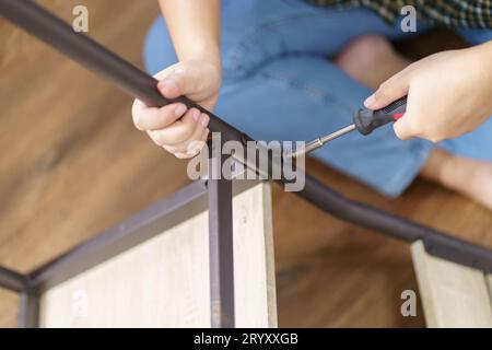 Asiatische Frau repariert Möbel-Renovierung selbst, indem sie Ausrüstung zum selbermachen von Möbeln verwendet, die zu Hause auf dem Boden sitzen Stockfoto