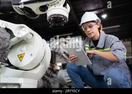 Eine Ingenieurin installiert ein Programm auf einem Roboterarm in einem Roboterlager. Und prüfen Sie die Funktion, bevor Sie die Maschine t senden Stockfoto