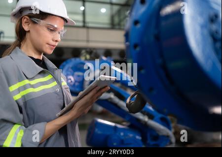 Eine Ingenieurin installiert ein Programm auf einem Roboterarm in einem Roboterlager. Und prüfen Sie die Funktion, bevor Sie die Maschine t senden Stockfoto