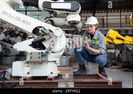 Eine Ingenieurin installiert ein Programm auf einem Roboterarm in einem Roboterlager. Und prüfen Sie die Funktion, bevor Sie die Maschine t senden Stockfoto