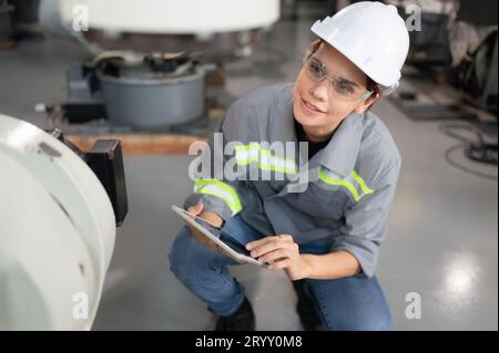 Eine Ingenieurin installiert ein Programm auf einem Roboterarm in einem Roboterlager. Und prüfen Sie die Funktion, bevor Sie die Maschine t senden Stockfoto