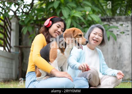 Familienurlaub, Mutter, Tochter und Beagle Hündchen entspannen sich am Wochenende im Vorgarten. Stockfoto