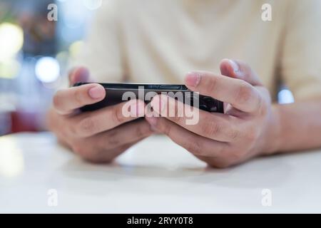 Mann, der auf dem Handy spielt. Gamer Boy, der Videospiele spielt und SmartphoneÂ mobile Geräte hält. Mobiltelefontechnik Stockfoto