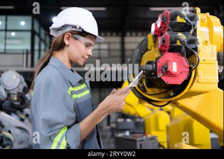 Eine Ingenieurin installiert ein Programm auf einem Roboterarm in einem Roboterlager. Und prüfen Sie die Funktion, bevor Sie die Maschine t senden Stockfoto