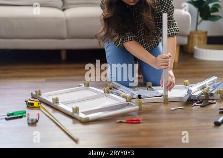 Asiatische Frau repariert Möbel-Renovierung selbst, indem sie Ausrüstung zum selbermachen von Möbeln verwendet, die zu Hause auf dem Boden sitzen Stockfoto
