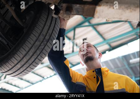 Autoreparaturmechaniker das Laufwerk des Fahrzeugs wird auf Schäden durch schwere Kollisionen überprüft. Stockfoto