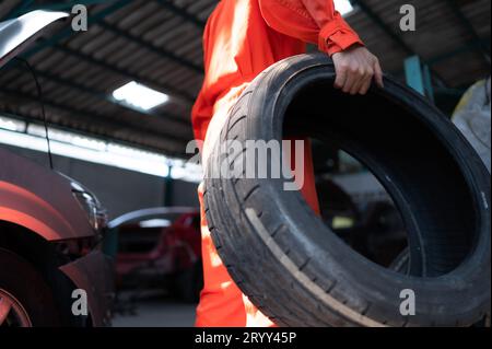 Ein Automechaniker überprüft den Zustand eines Autoreifens, bevor er ihn auf einem Fahrzeug absetzt. Stockfoto