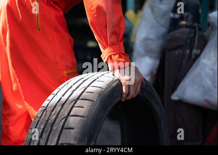 Ein Automechaniker überprüft den Zustand eines Autoreifens, bevor er ihn auf einem Fahrzeug absetzt. Stockfoto