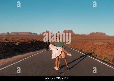 Glückliches Paar auf der berühmten Straße zum Monument Valley in Utah bei ihrer Reise auf dem Canyon in den USA. Malerische Autobahn im Monument Valley Tri Stockfoto