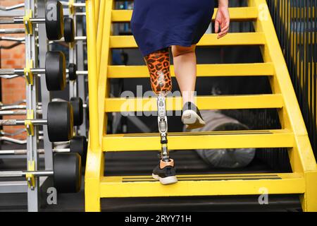 Junge Frau mit einer Beinprothese, die trainiert ist, Treppen hoch- und runterzugehen, um die gemeinsame Anwendung von Prothesen mit norma zu üben Stockfoto