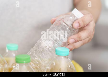 Recyceln Sie den umweltfreundlichen Zero Concept-Mann, der leere Plastikflasche in den Recyclingbehälter mit gelben Mülltüten zu Hause wirft Stockfoto