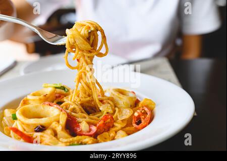 Frau essen Meeresfrüchte Spaghetti weiße Sauce mit einer Gabel im italienischen Restaurant. Essen und Küche Konzept. Stockfoto