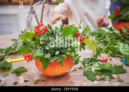 Meisterkurs über die Herstellung von Blumensträußen. Herbststrauß in einem Kürbis. Blumenarrangements, die schöne Sträuße mit Ihrem eigenen han kreieren Stockfoto