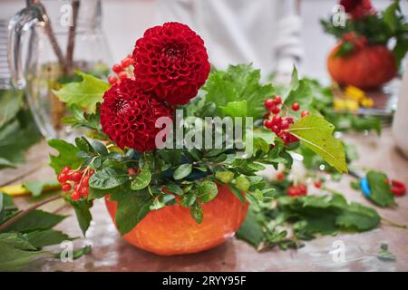 Meisterkurs über die Herstellung von Blumensträußen. Herbststrauß in einem Kürbis. Blumenarrangements, die schöne Sträuße mit Ihrem eigenen han kreieren Stockfoto