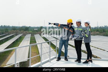 Auf dem Dach eines großen Solarspeichers baut Ein Team von Elektrotechnikern, die Solarpaneele inspizieren Stockfoto