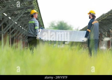 Ingenieure und Techniker entladen reparierte Solarpaneele, die auf den Reihen von Solarzellen installiert werden sollen, die an Hunderten von Wechselstrom angeordnet sind Stockfoto