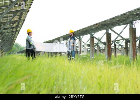 Ingenieure und Techniker entladen reparierte Solarpaneele, die auf den Reihen von Solarzellen installiert werden sollen, die an Hunderten von Wechselstrom angeordnet sind Stockfoto