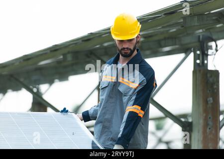 Ingenieure und Techniker entladen reparierte Solarpaneele, die auf den Reihen von Solarzellen installiert werden sollen, die an Hunderten von Wechselstrom angeordnet sind Stockfoto