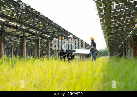 Ingenieure und Techniker entladen reparierte Solarpaneele, die auf den Reihen von Solarzellen installiert werden, die auf Hunderten von A angeordnet sind Stockfoto