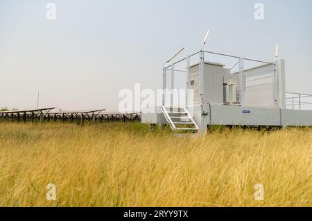 Das Feld der Solarpaneele mit einer Energiespeicherstation, die sich in der Mitte eines Solarzellenpaneels auf einer Fläche von Hunderten von A befindet Stockfoto
