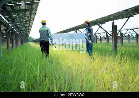 Ingenieure und Techniker entladen reparierte Solarpaneele, die auf den Reihen von Solarzellen installiert werden sollen, die an Hunderten von Wechselstrom angeordnet sind Stockfoto