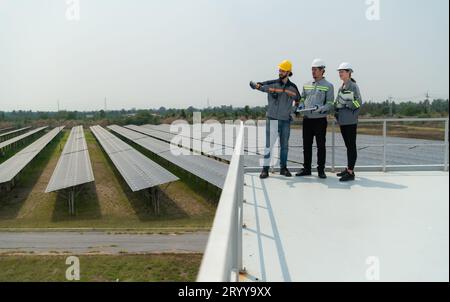 Auf dem Dach eines großen Solarspeichers baut Ein Team von Elektrotechnikern, die Solarpaneele inspizieren Stockfoto