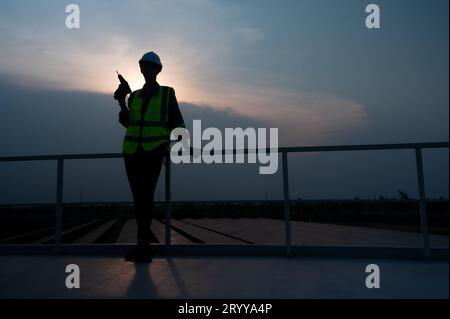 Elektroingenieure inspizieren Solarpaneele in 100 Hektar Gras auf dem Dach des Energiespeichers am Abend Stockfoto