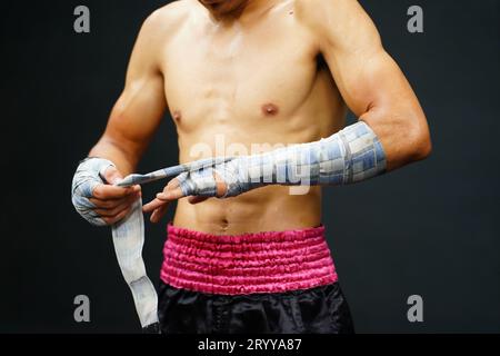 Muay Thai, die Kampfkunst Thailands, die Hände vor dem Anziehen von Boxerhandschuhen mit einem Tuch umwickeln hilft, die Auswirkungen zu reduzieren Stockfoto