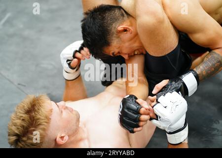 Mixed Martial Art, wenn es die gefallene Partei ist, dann finden Sie einen Weg, das Bein zu verwenden, um dem Gegner den Hals zu binden. Macht den Gegner Stockfoto