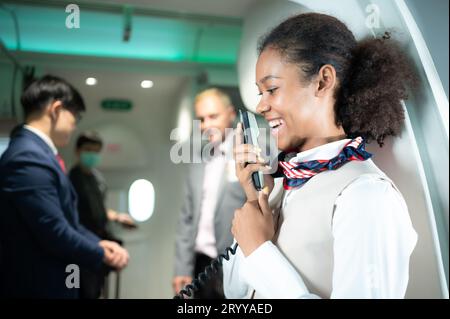 Der Flugbegleiter spricht über einen Lautsprecher, um Passagiere willkommen zu heißen und Ratschläge zur Flugreise zu geben Stockfoto