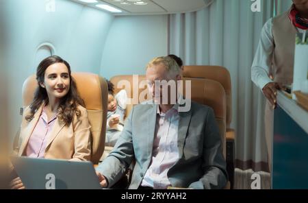 Die Flugbegleiterin serviert den Passagieren Speisen und Getränke Stockfoto