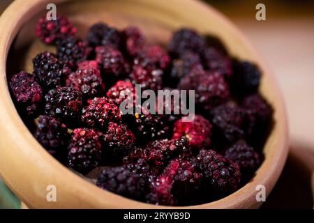 Eine detailgetreue Aufnahme aus nächster Nähe mit einer Schüssel voller frischer, roter Brombeeren. Der Fokus ist scharf, wodurch die Textur und die satten Farben des hervorgehoben werden Stockfoto