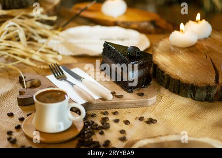 Schokoladenkuchen und türkischer Kaffee, angereichert mit verstreuten Kaffeebohnen. Die Umgebungsbeleuchtung hebt die Texturen hervor. Stockfoto