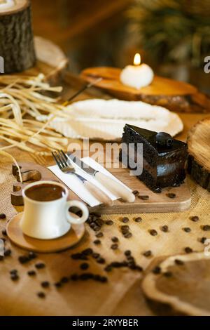 Schokoladenkuchen und türkischer Kaffee, angereichert mit verstreuten Kaffeebohnen. Die Umgebungsbeleuchtung hebt die Texturen hervor. Stockfoto