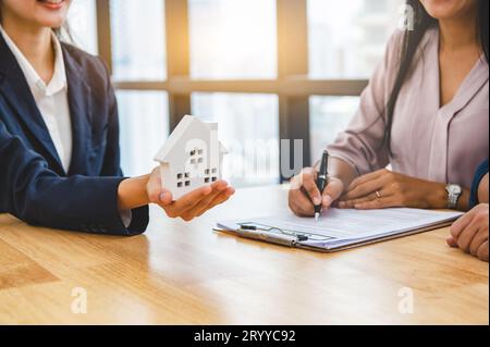 Immobilienmakler bieten dem Kunden ein privates Haus an, bevor sie Vertragsdokumente für Mietobjekte unterzeichnen. Ownne Stockfoto