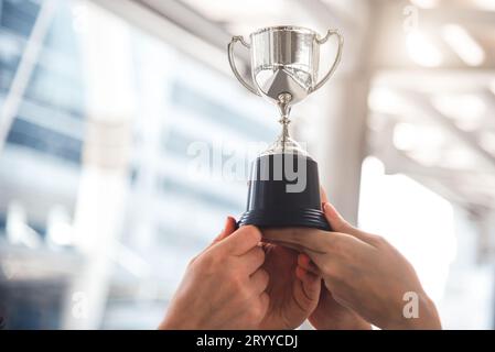 Champion Silver Trophäe für den zweiten Sieger mit Händen von Sportspielern im Hintergrund des Sportstadions. Erfolgs- und Leistungskonzept Stockfoto