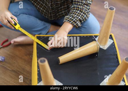 Asiatische Frau repariert Möbel-Renovierung selbst, indem sie Ausrüstung zum selbermachen von Möbeln verwendet, die zu Hause auf dem Boden sitzen Stockfoto