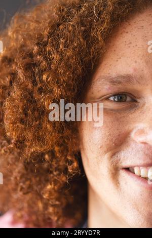 Ein halbes Porträt eines glücklichen, birassischen Mannes mit lockigem rotem Haar und Sommersprossen, die lächeln Stockfoto