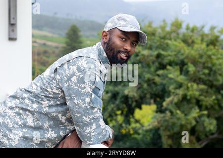 Porträt eines glücklichen afroamerikanischen Soldaten, der Militäruniform auf der Terrasse trägt Stockfoto