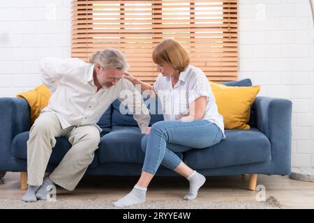 Ein älteres Ehepaar mit einem Mann, der an Rückenschmerzen leidet, ohne Kinder zu versorgen, muss jeder helfen und sich um jedes kümmern Stockfoto