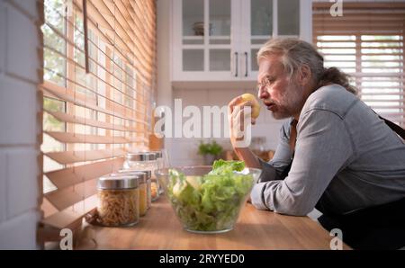 Opa in der Küche mit natürlichem Licht, bereitet sich auf das Abendessen für die Familie vor. Stockfoto