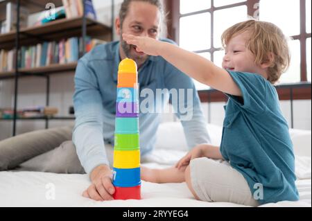 Vater und kleiner Junge haben Spaß beim Spielen mit deinen neuen Spielzeugen im Schlafzimmer. Spielzeug, das die Denkfähigkeit von Kindern verbessert Stockfoto