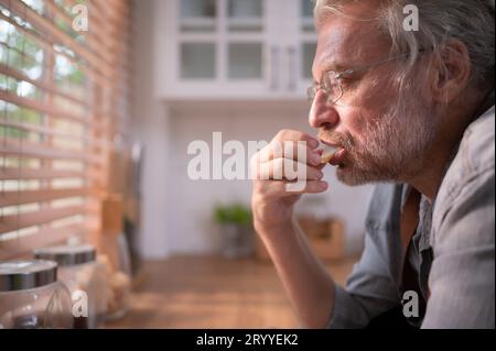 Opa in der Küche mit natürlichem Licht, bereitet sich auf das Abendessen für die Familie vor. Stockfoto