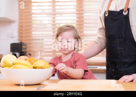 Mom und Dad in der Küche des Hauses mit ihren kleinen Kindern. Hab Spaß daran, zusammen Abendessen zu machen. Stockfoto