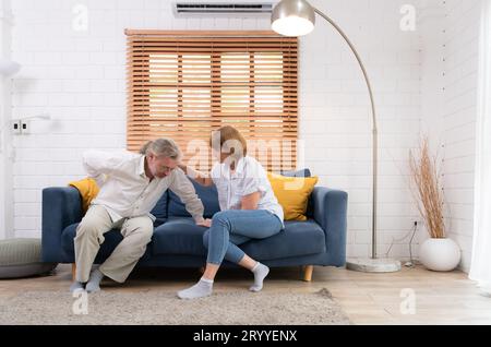 Ein älteres Ehepaar mit einem Mann, der an Rückenschmerzen leidet, ohne Kinder zu versorgen, muss jeder helfen und sich um jedes kümmern Stockfoto