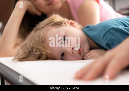 Nachdem der kleine Junge aus seinem Nickerchen aufwacht, machen Vater und Mutter in seinem Schlafzimmer angenehme Aktivitäten. Stockfoto