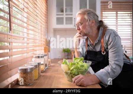 Opa in der Küche mit natürlichem Licht, bereitet sich auf das Abendessen für die Familie vor. Stockfoto