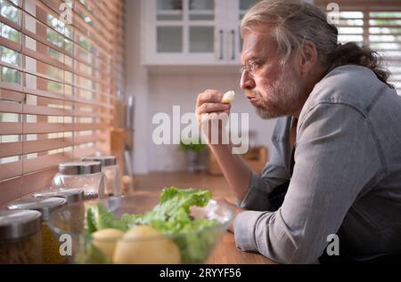 Opa in der Küche mit natürlichem Licht, bereitet sich auf das Abendessen für die Familie vor. Stockfoto