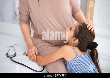 Niedliche Tochter, die Mutter umarmt und die Stimme des Babys im Mutterbauch hört, um das Gesicht der Mutter zu überprüfen und zu betrachten. Schwanger und p Stockfoto